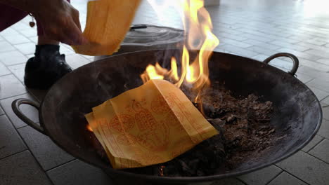 close-up shot, put joss paper into the flame