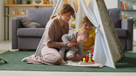 mom and little kids playing with toy in teepee