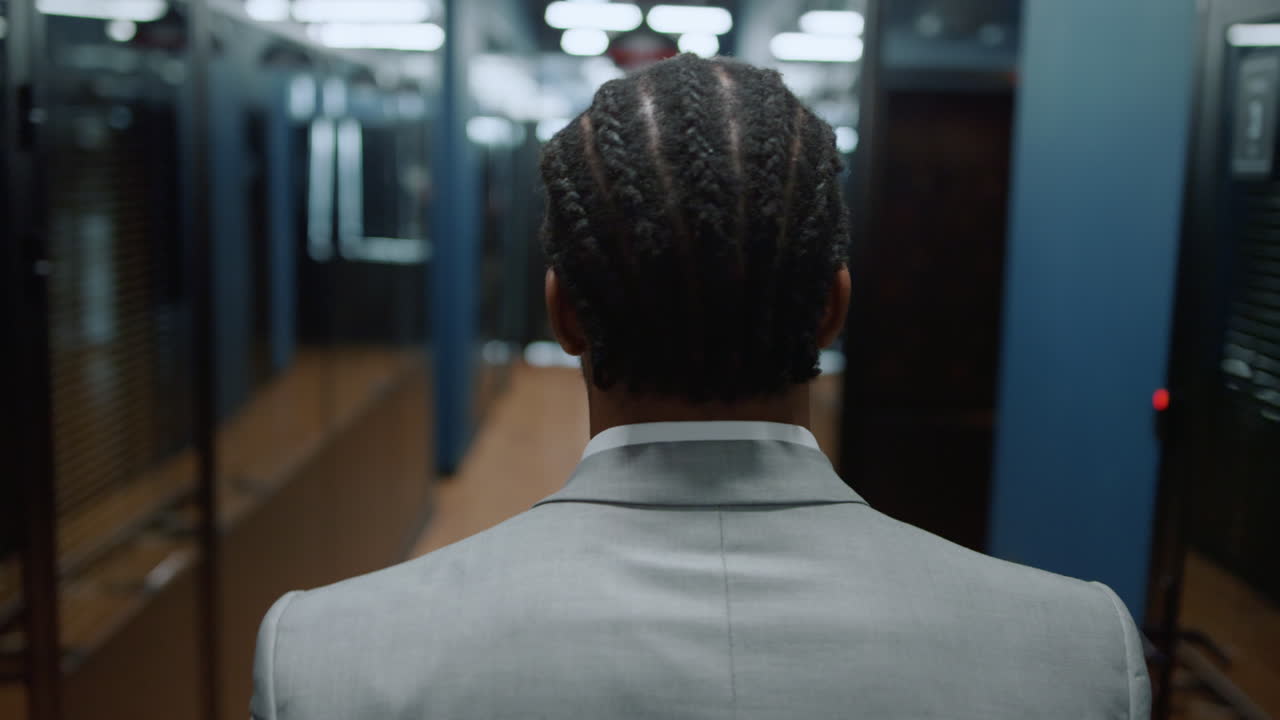 Back view afro man going on meeting in office. Businessman walking on meetup