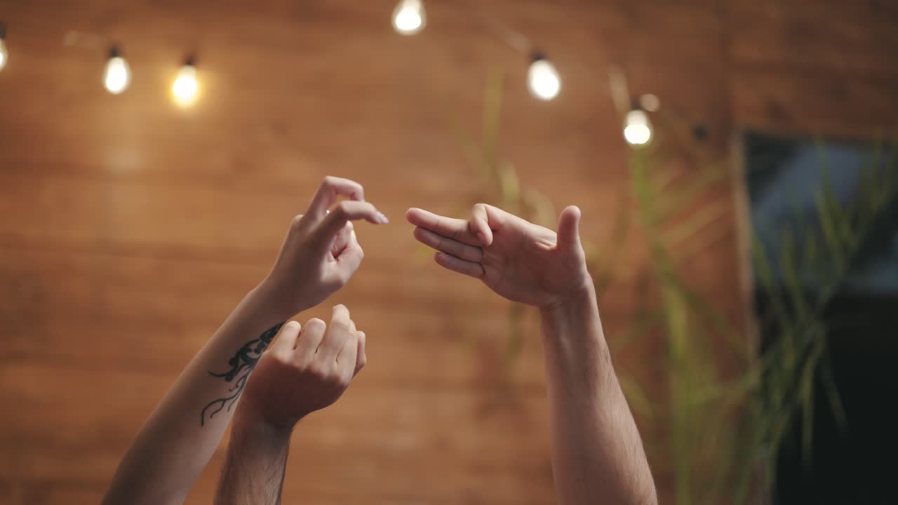 Male's and female's hands making dog gestures playing together. Couple in love shows gestures by their arms on the wooden wall background.