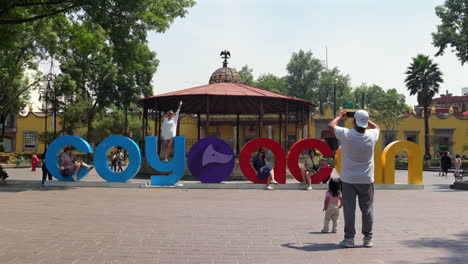 tourists take pictures at coyoacan borough's welcome sign at plaza hidalgo in mexico city