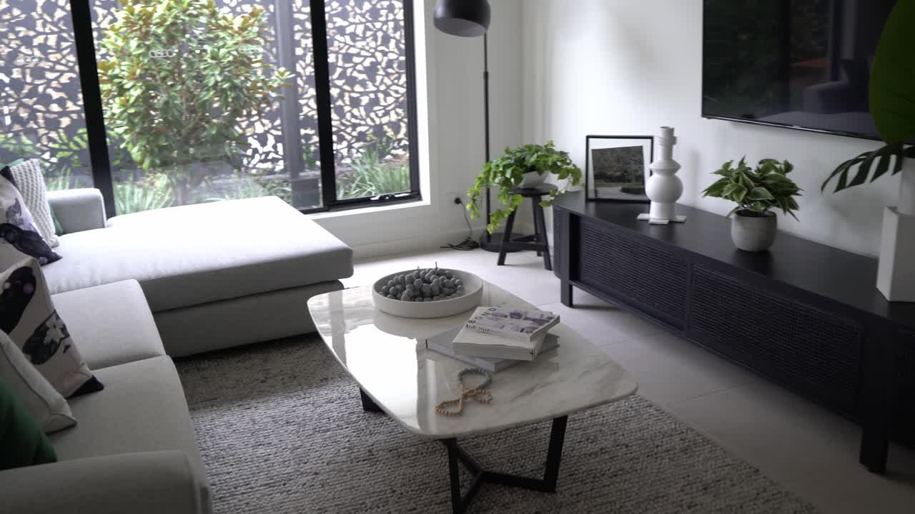 Design open space in cucina e soggiorno con divano color crema e TV.