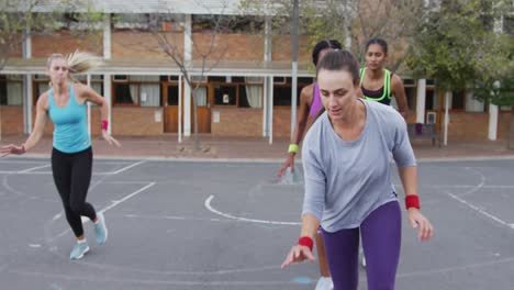 diverse female basketball team playing match, dribbling ball