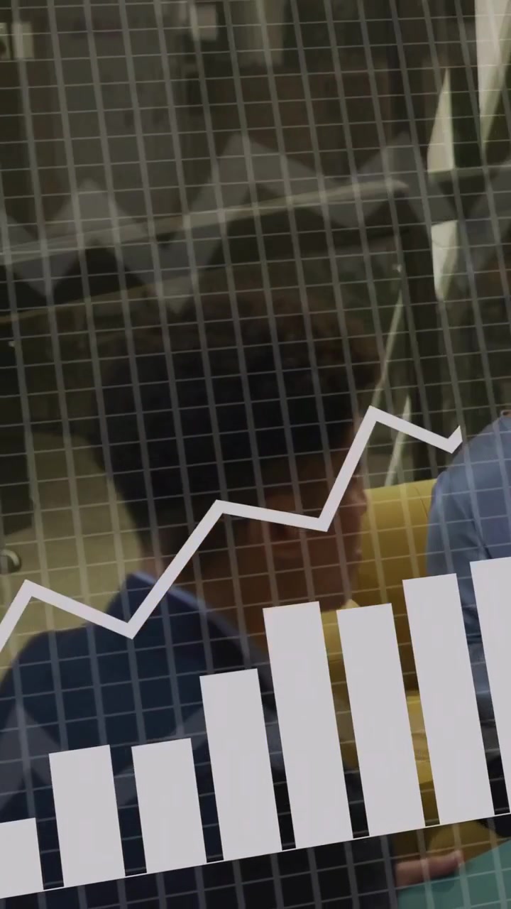 Vertical video: Man sitting on yellow couch, peer tapping device, overlaying business charts