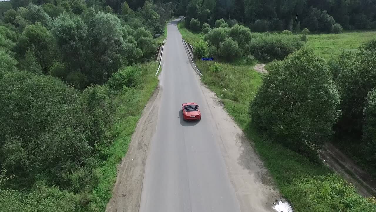 Auto rossa su ponte di strada di campagna