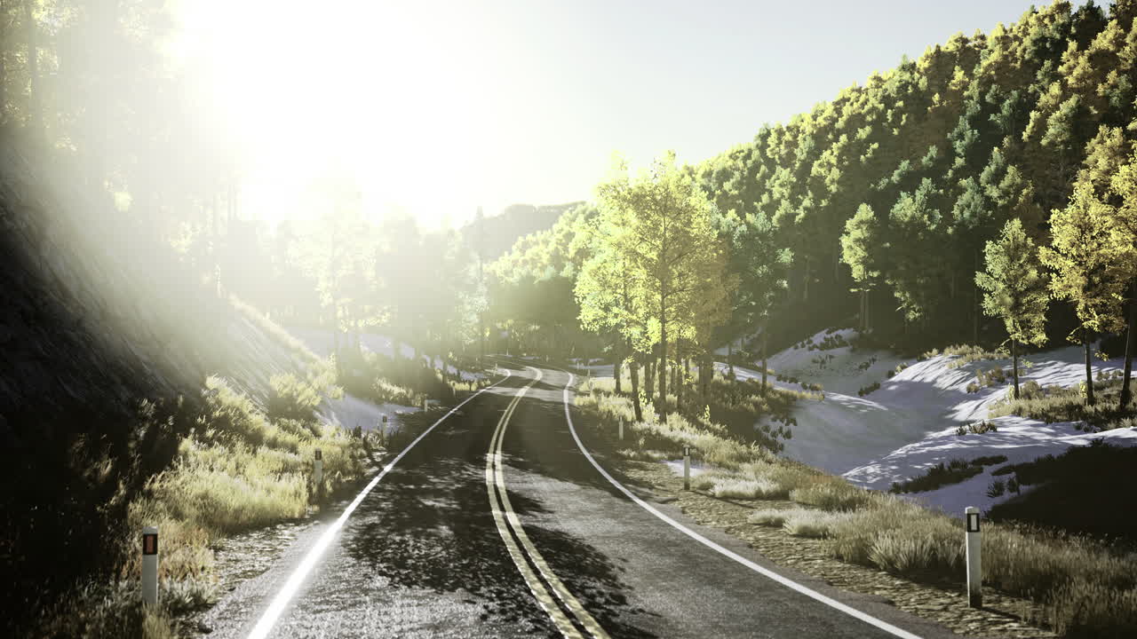 Scenic winding road through green hills with sunlight shining in background