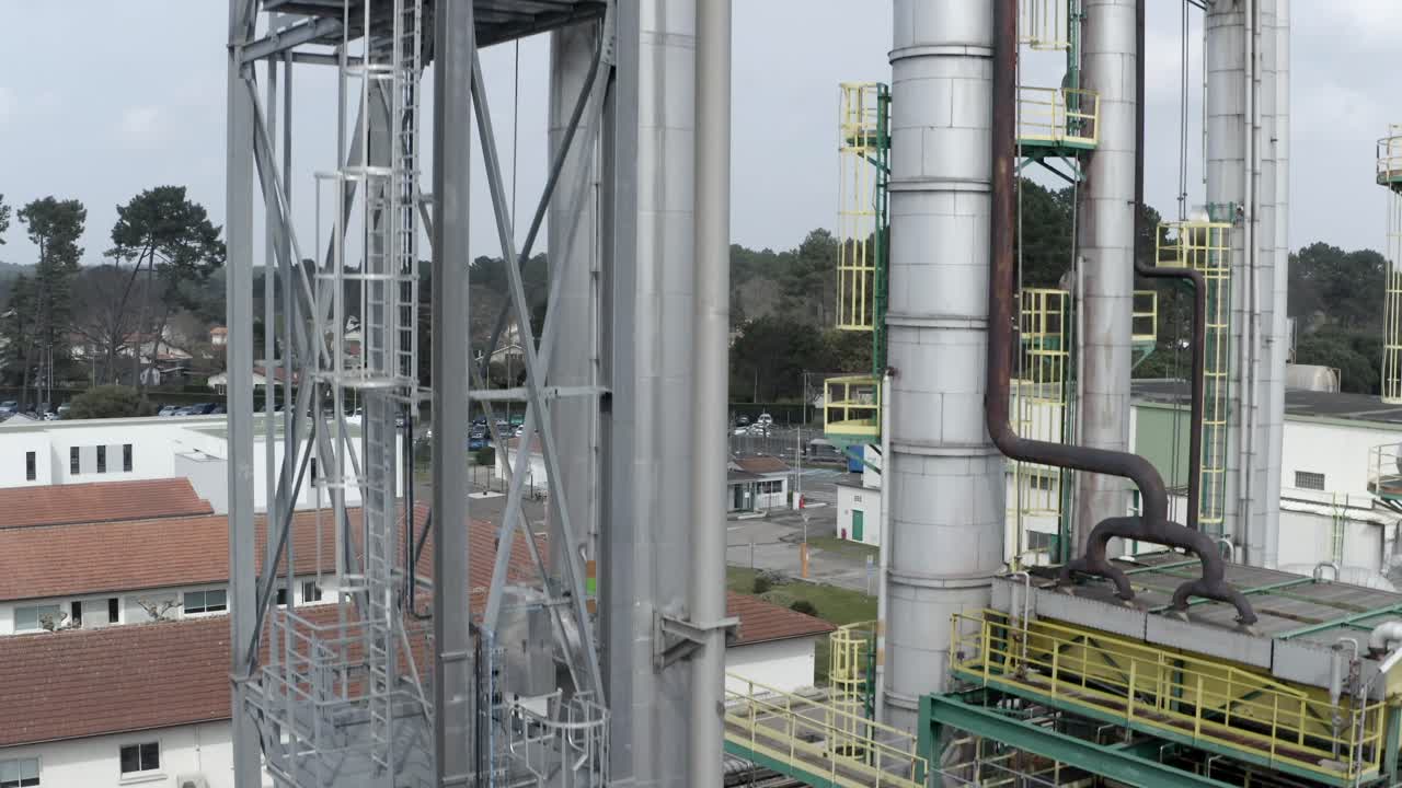 Aerial drone ascending view focusing on tall industrial towers, silos, and intricate piping at the DRT Factory in Veille-Saint-Girons, France