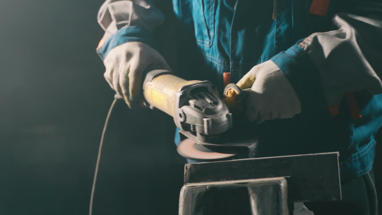 cerrajero en ropa especial y gafas de protección trabaja en la producción. procesamiento de metales con molienda angular. chispas en la metalurgia