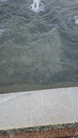 abstract close up of water fountain surface in park. shooting vertical video.