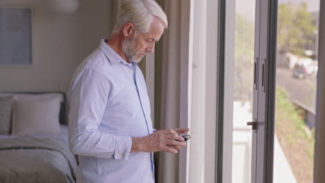 mature-man-using-smartphone-at-home-texting-sharing-messages-on-social-media-enjoying-mobile-phone-communication