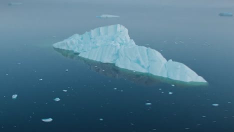imágenes aéreas de un iceberg blanco en el océano ártico agua del mar mientras la cámara del dron vuela a su alrededor y revela piezas más pequeñas de hielo