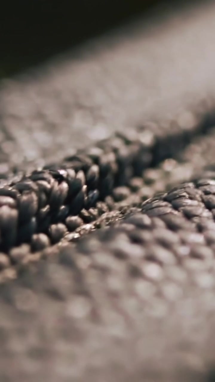 Vertical video: Pulling focus, camera revealing woven seam in studio with yarn loops showing detail