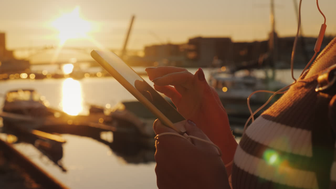 Hands Of A Woman With A Smartphone On The Background Of A Pier With Yachts At Sunset 4k Video