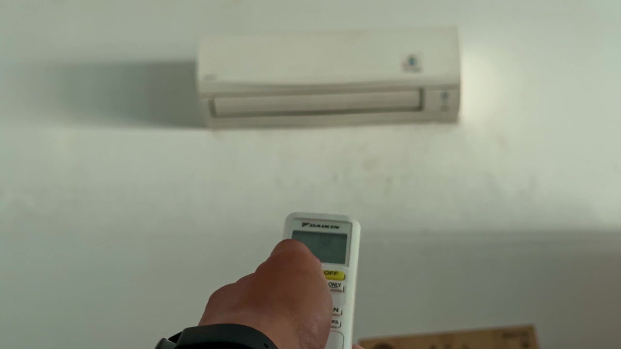 Person operating air conditioner remote close up, activating cooling system, home comfort technology concept.