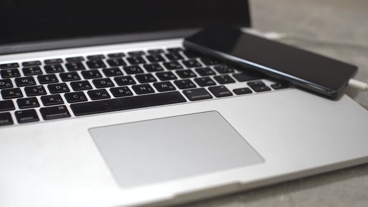 hand steckt das ladegerät in das handy gegen den laptop