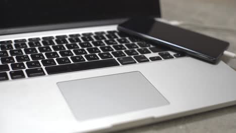 hand-plugging-the-charger-into-cell-phone-against-laptop-computer