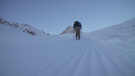 skier tours up the mountain on an early morning in tignes, france on a sunny day