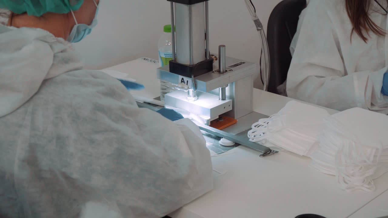 보호복과 장갑을 낀 남자가 자동 기계에 안면 마스크를 부었다