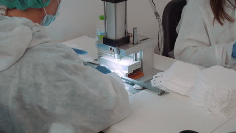 un hombre con traje protector y guantes vertió máscaras faciales en una máquina automática