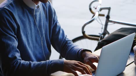 man listening music while using laptop on table 4k
