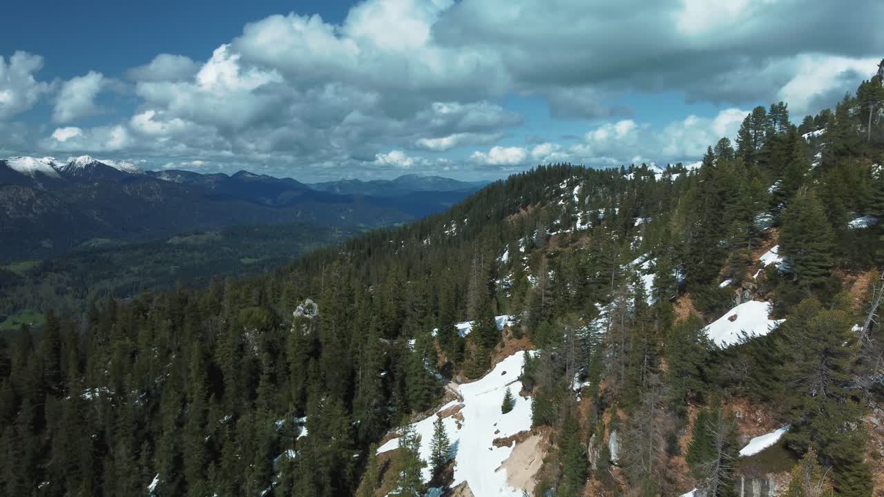 amplio y épico vuelo panorámico de montaña por encima del pintoresco castillo de baviera elmau y picos de bosques verdes en los alpes bávaros austríacos en un día nublado y soleado a lo largo de árboles, rocas y colinas en la naturaleza alpina