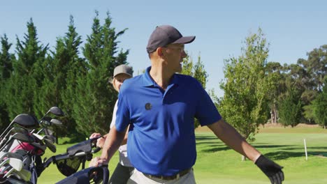 Caucasian-senior-couple-walking-with-their-golf-bags-at-golf-course-on-a-bright-sunny-day