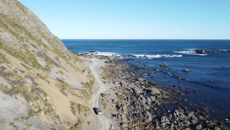 slowly following a truck as it drives along a gravel coastal road