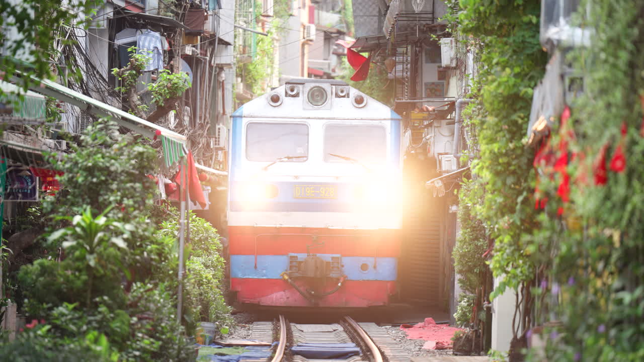 Train approaches down narrow alleyway in famous train street in Hanoi, Vietnam