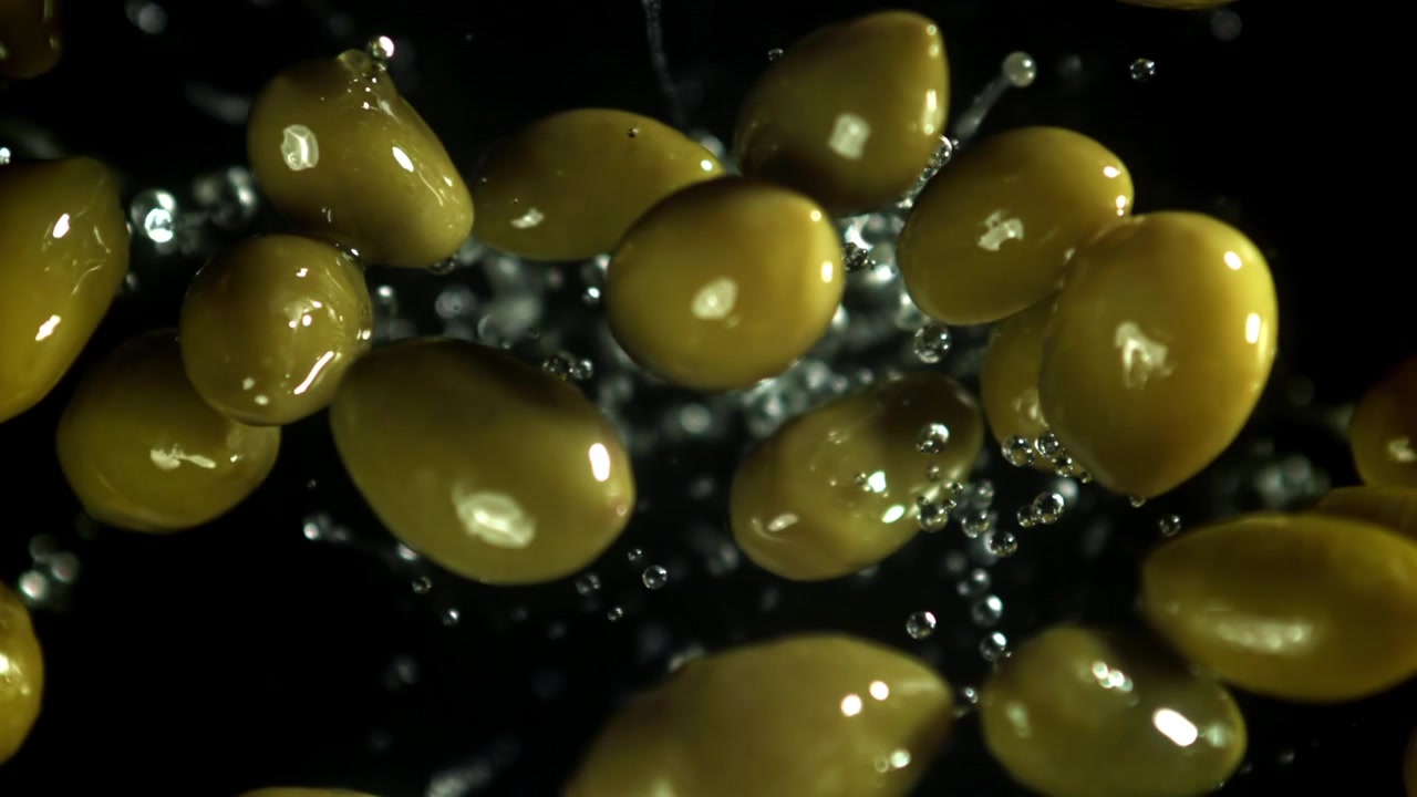 Olive verdi fresche con goccioline d'acqua che schizzano al rallentatore