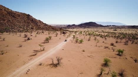 Panorámica-Aérea-Revela-Un-Vehículo-Todoterreno-Que-Explora-El-Implacable-Paisaje-Desértico