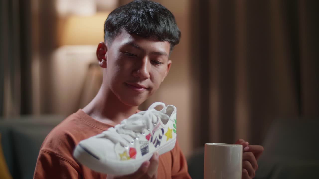 집에서 데스크 컴퓨터에서 일하면서 커피를 마시는 아시아 소년 신발 디자이너의 근접 사진