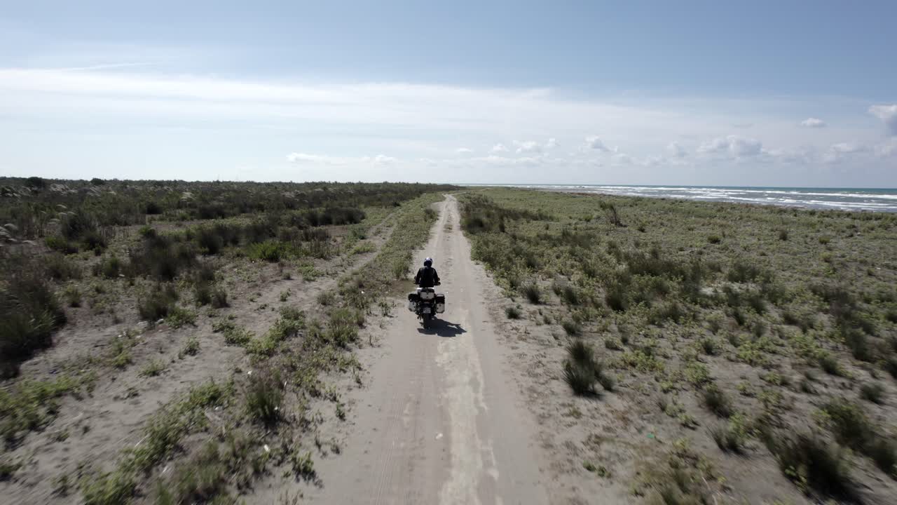 video con drone "sígueme" a un motociclista conduciendo por la playa