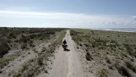 video with drone "follow me" to a motorcyclist driving along the beach