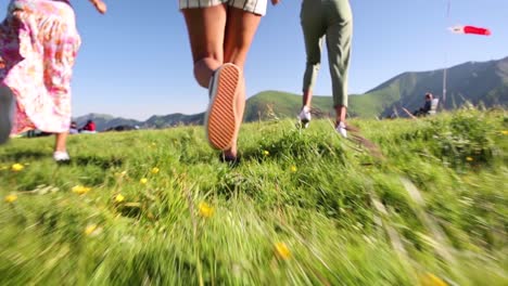 slow motion follow shot of family running on green meadow during sunny day - low angle track shot - georgia,kazbegi