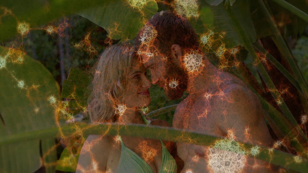 Under tropical leaves, couple embracing with glowing animation overlay patterns