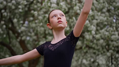 young ballerina posing outdoors in spring