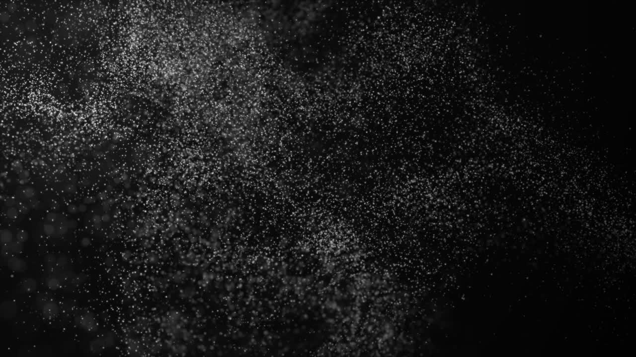 Dust particles floating on black background.