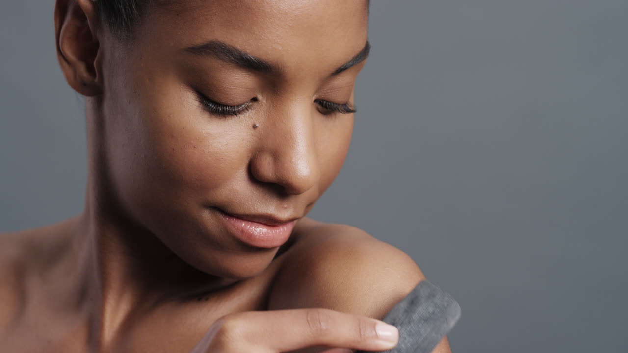 retrato de perto de uma mulher afro-americana deslumbrante tocando suavemente a pele com carvão acariciando a pele suave e natural desfrutando da esfoliação sensual conceito de beleza