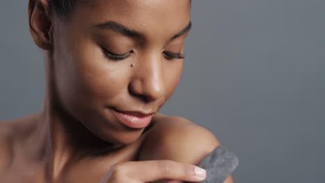 close up portrait gorgeous african american woman gently touching skin with charcoal caressing soft natural complexion enjoying sensual exfoliation beauty concept