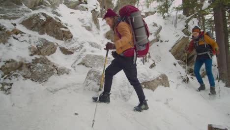 couple hiking on steep trail in mountains on winter day