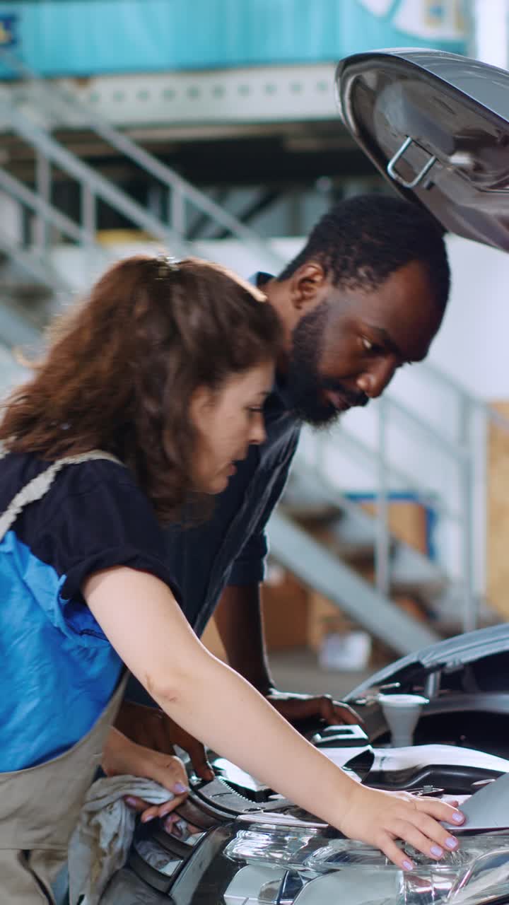 Vertical video Engineer in garage changes car motor oil