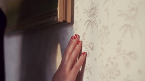 hand touching floral wallpaper