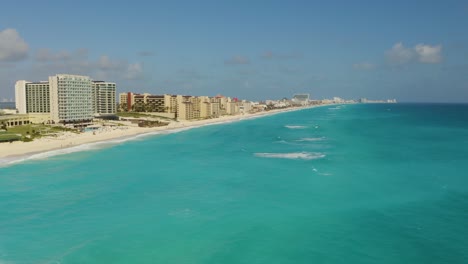 Drohne-Fliegt-über-Kristallklarem-Wasser-In-Richtung-Sandküste-Mit-Hotels