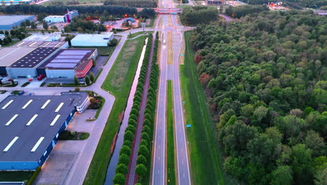 aerial view of a highway with greenery. a wide highway runs through lush greenery, lined with trees and buildings, glowing in soft evening light