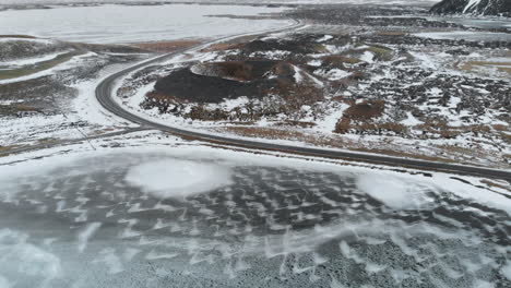 Aerial-View-of-Frozen-Lake,-Road-and-Volcanic-Crater-in-Highlands-of-Iceland