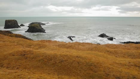 the beautiful waves of iceland by the brown mountain landscape and rocky shore - wide rolling