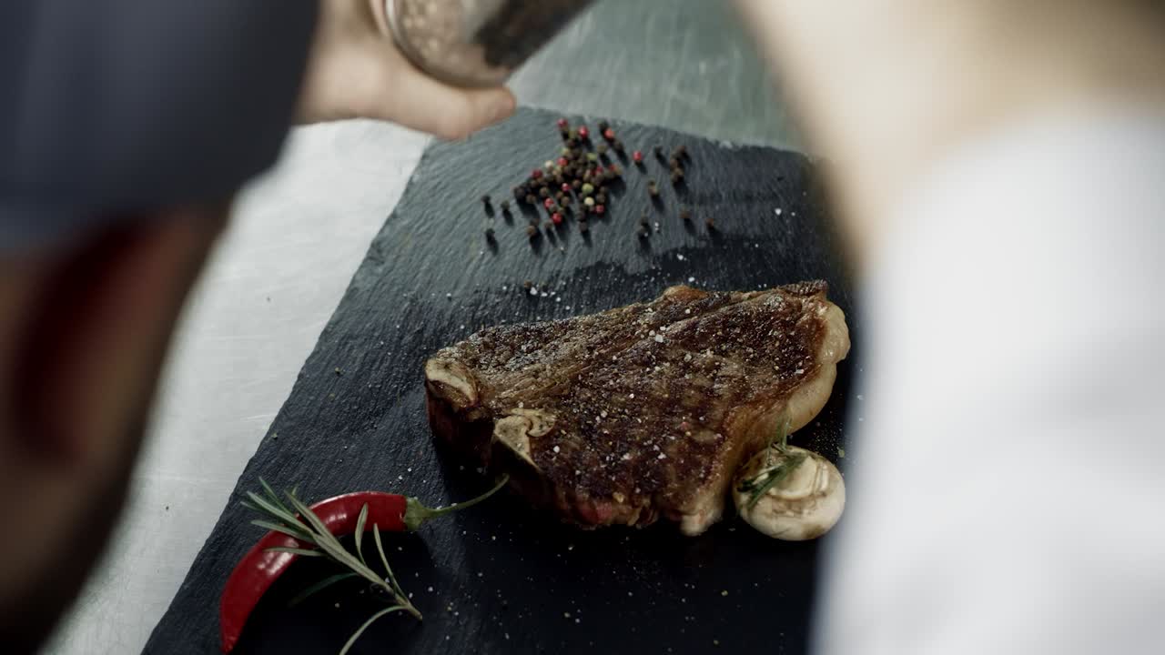 chef picando carne en la tabla de corte de piedra. manos de hombre picando rayas a la parrilla
