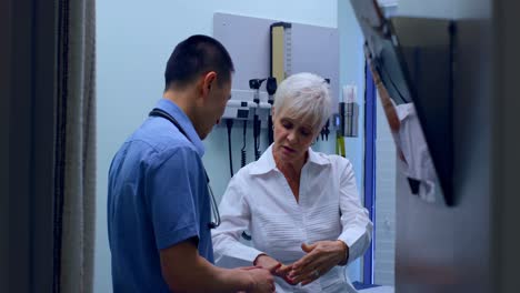 joven médico asiático examinando a un paciente anciano en la clínica 4k