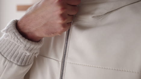 closeup of a man closing the zipoer on his jacket