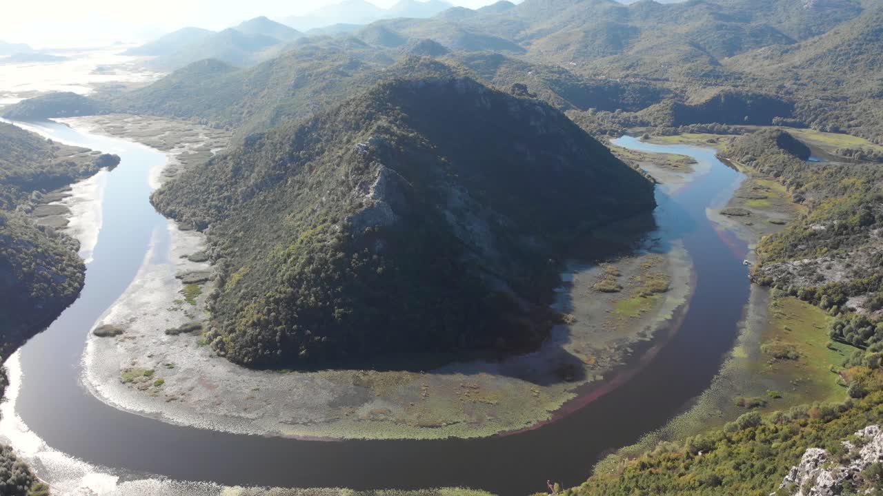 An aerial view of Lake Skadar in Montenegro on the bend of the river during a beautiful sunny day. Flying backwards to show the whole bend in the river from an aerial view